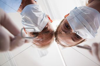 Dentist and assistant leaning over patient with tools