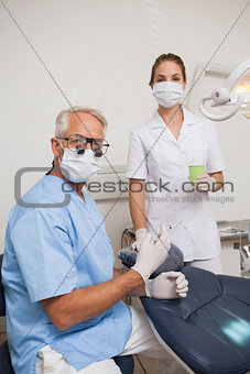 Dentist and assistant looking at camera by the chair