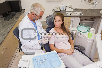 Dentist speaking with patient in the chair showing model of mouth