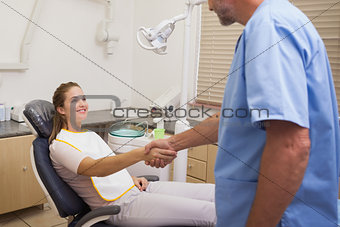Dentist shaking hands with his patient in the chair