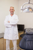 Dentist smiling at camera beside chair