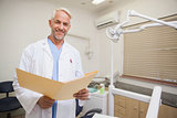 Dentist smiling at camera holding folder