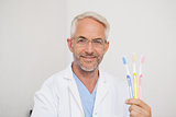 Dentist smiling at camera holding toothbrushes