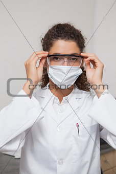 Dentist putting on protective glasses looking at camera