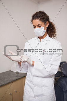 Dentist putting on surgical gloves