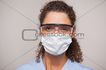 Dentist in surgical mask and protective glasses looking at camera