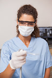 Dentist in mask and protective glasses holding drill