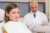 Pediatric dentist and little girl sitting in chair