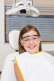 Little girl sitting in dentists chair wearing protective glasses