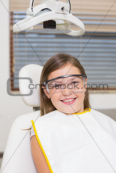 Little girl sitting in dentists chair wearing protective glasses