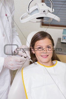 Little girl sitting in dentists chair smiling at camera