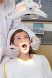 Pediatric dentist examining a patients teeth in the dentists chair