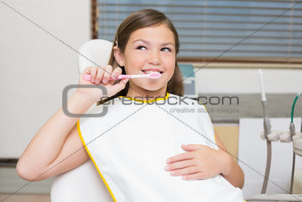Little girl holding toothbrush in dentists chair