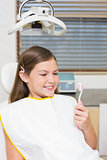 Little girl holding toothbrush in dentists chair
