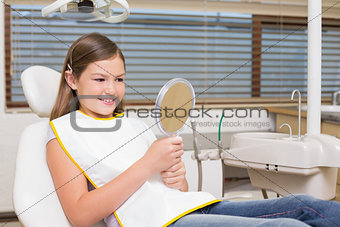 Little girl holding mirror in dentists chair