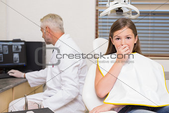 Terrified little girl looking at camera in dentists chair