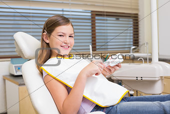 Little girl sitting in dentists chair looking at model teeth