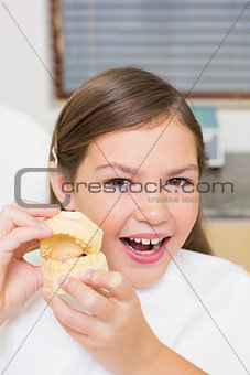 Little girl sitting in dentists chair holding model teeth