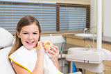 Little girl sitting in dentists chair holding model teeth