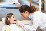 Pediatric dentist examining little girls teeth in the dentists chair