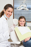 Pediatric dentist and little girl in the dentists chair smiling at camera