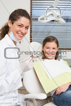 Pediatric dentist and little girl in the dentists chair smiling at camera