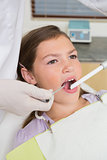 Pediatric dentist examining a little girls teeth in the dentists chair