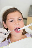 Pediatric dentist examining a little girls teeth in the dentists chair