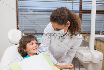 Pediatric dentist smiling down at little boy in chair
