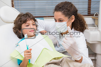Pediatric dentist showing little boy in chair the toothrbrush