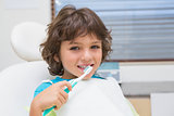 Little boy in dentists chair using toothrbrush