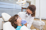 Pediatric dentist examining a little boys teeth in the dentists chair