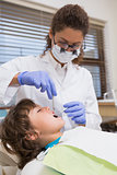 Pediatric dentist examining a little boys teeth in the dentists chair