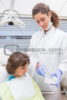 Pediatric dentist showing little boy teeth model