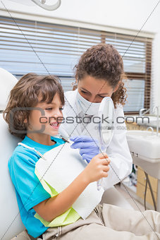 Pediatric dentist showing little boy his teeth in the mirror