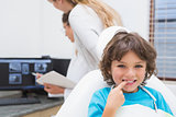 Little boy smiling at camera with mother and dentist in background