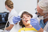 Pediatric dentist examining a little boys teeth with assistant behind