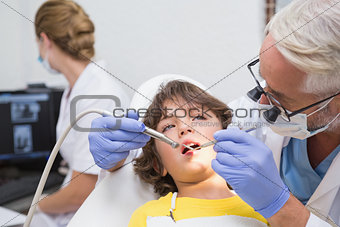 Pediatric dentist examining a little boys teeth with assistant behind