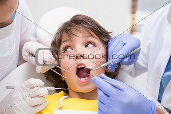 Pediatric dentist examining a little boys teeth with his assistant
