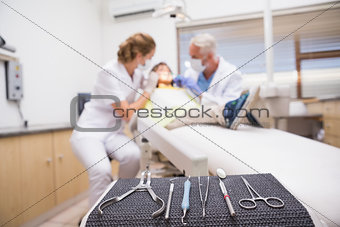 Pediatric dentist examining a little boys teeth with his assistant