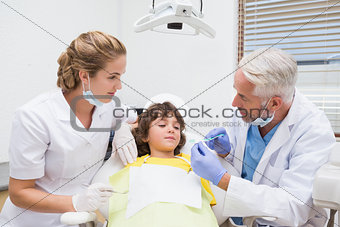Pediatric dentist showing little boy how to brush his teeth