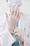 Dentist pulling on surgical gloves
