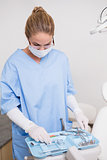 Dentist in blue scrubs looking at her tools