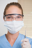 Dentist in surgical mask holding dental explorer