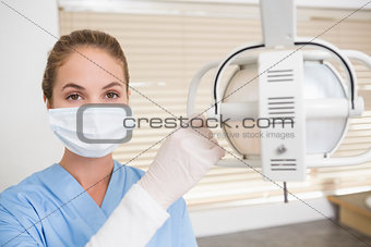 Dentist in surgical mask adjusting light