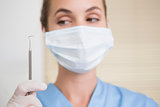 Dentist in surgical mask holding dental explorer