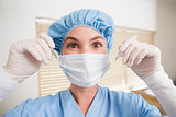 Dentist in surgical mask and cap holding dental tools