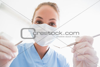 Dentist in surgical mask holding tools over patient