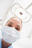 Dentist in surgical mask holding dental explorer over patient