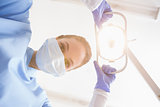 Dentist in surgical mask shining light over patient